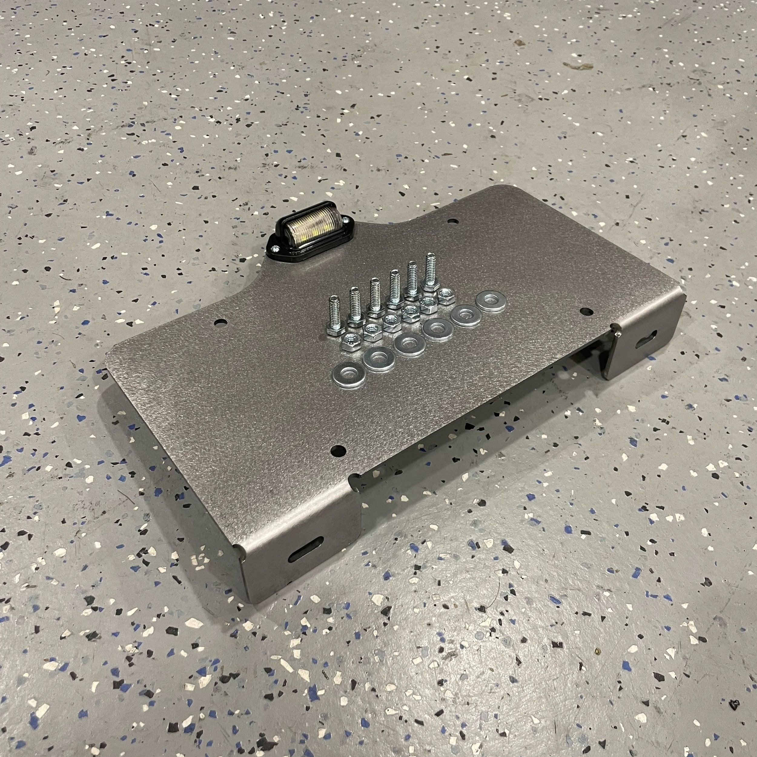 Heavy-duty steel bottom top mount license plate holder for trailers, flatbeds, RVs, and semi-trucks with LED light by Elevate Metalcraft.