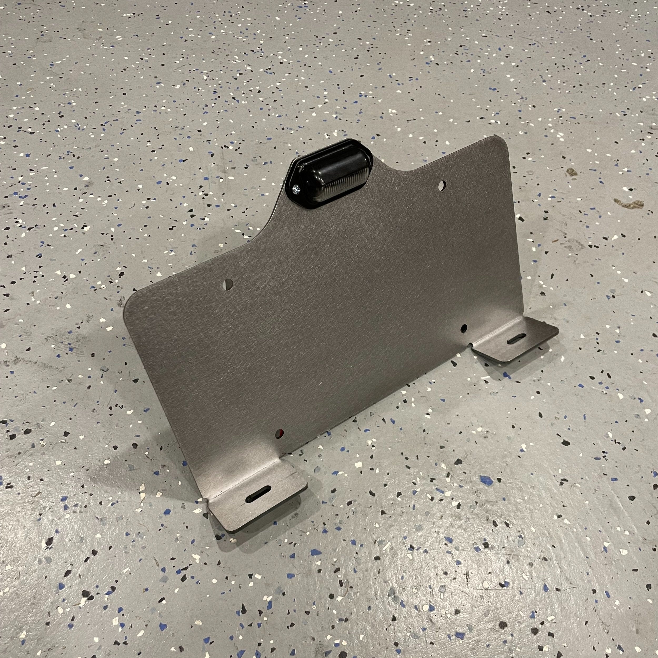Heavy-duty steel bottom top mount license plate holder for trailers, RVs, and semi-trucks with integrated LED light by Elevate Metalcraft.