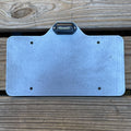 Heavy-duty steel license plate holder with LED light mounted on a flatbed trailer, suitable for RV, camper, and semi-truck.