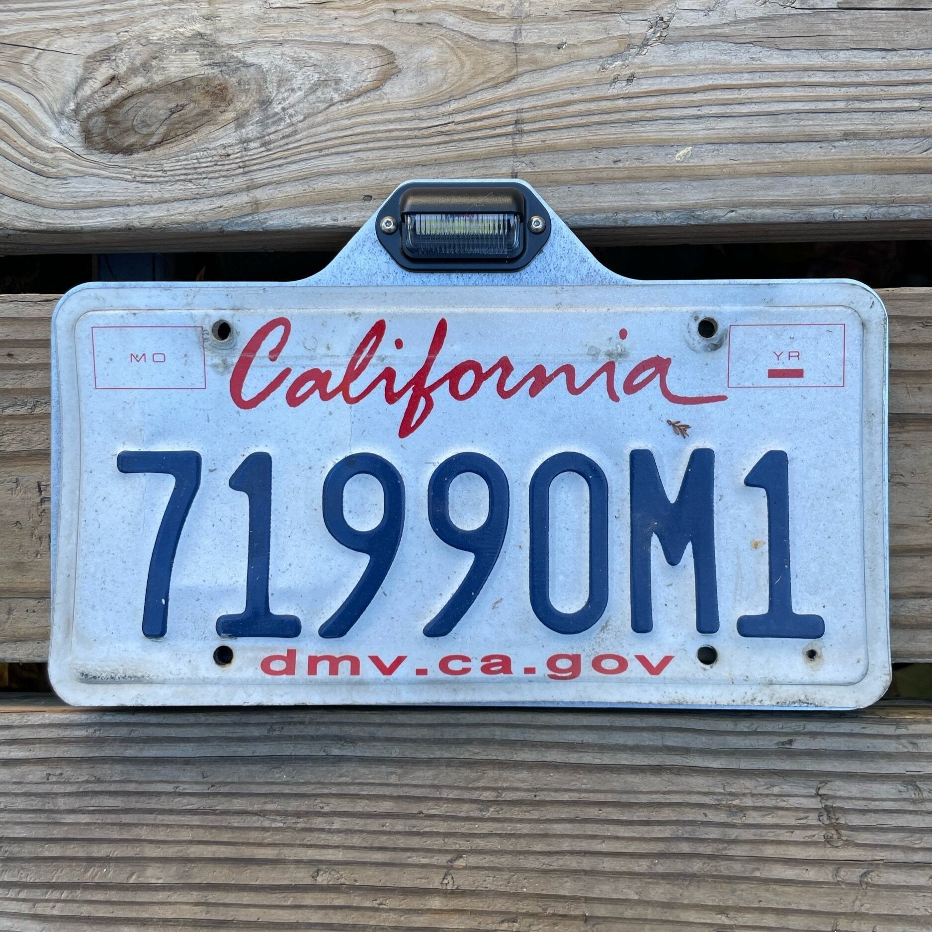 Heavy-duty steel license plate holder mount for trailers, RVs, and campers with bolt-on design and integrated LED light by Elevate Metalcraft.