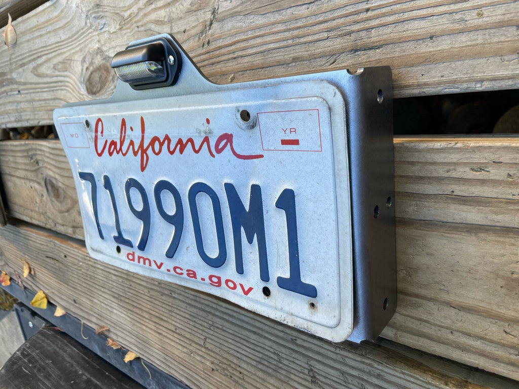 Heavy-duty steel side mount license plate holder for trailers, RVs, and semi-trailers with LED light on right side.