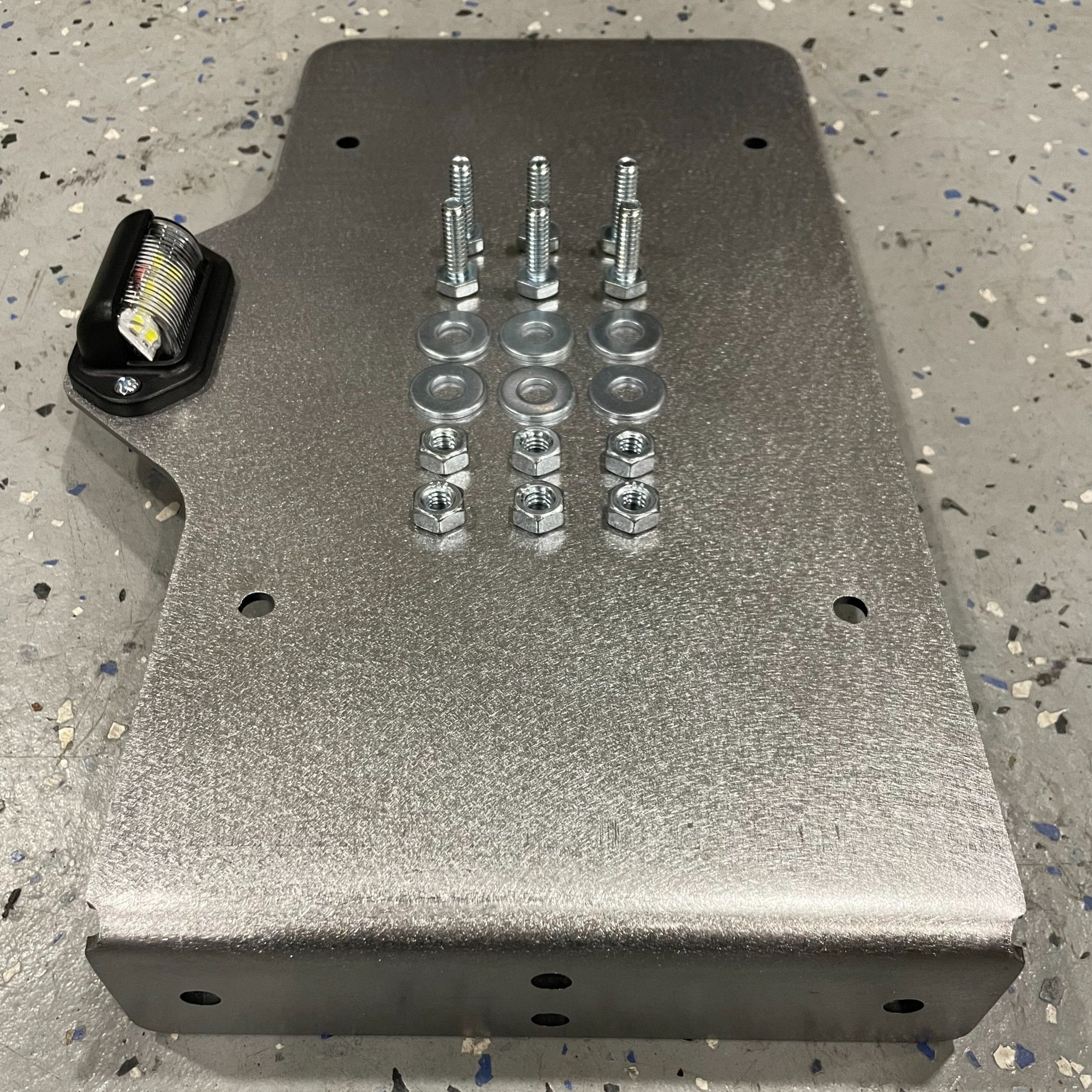 Heavy-duty steel side mount license plate holder for trailers, RVs, and semi-trucks with LED light, compatible with left or right side.