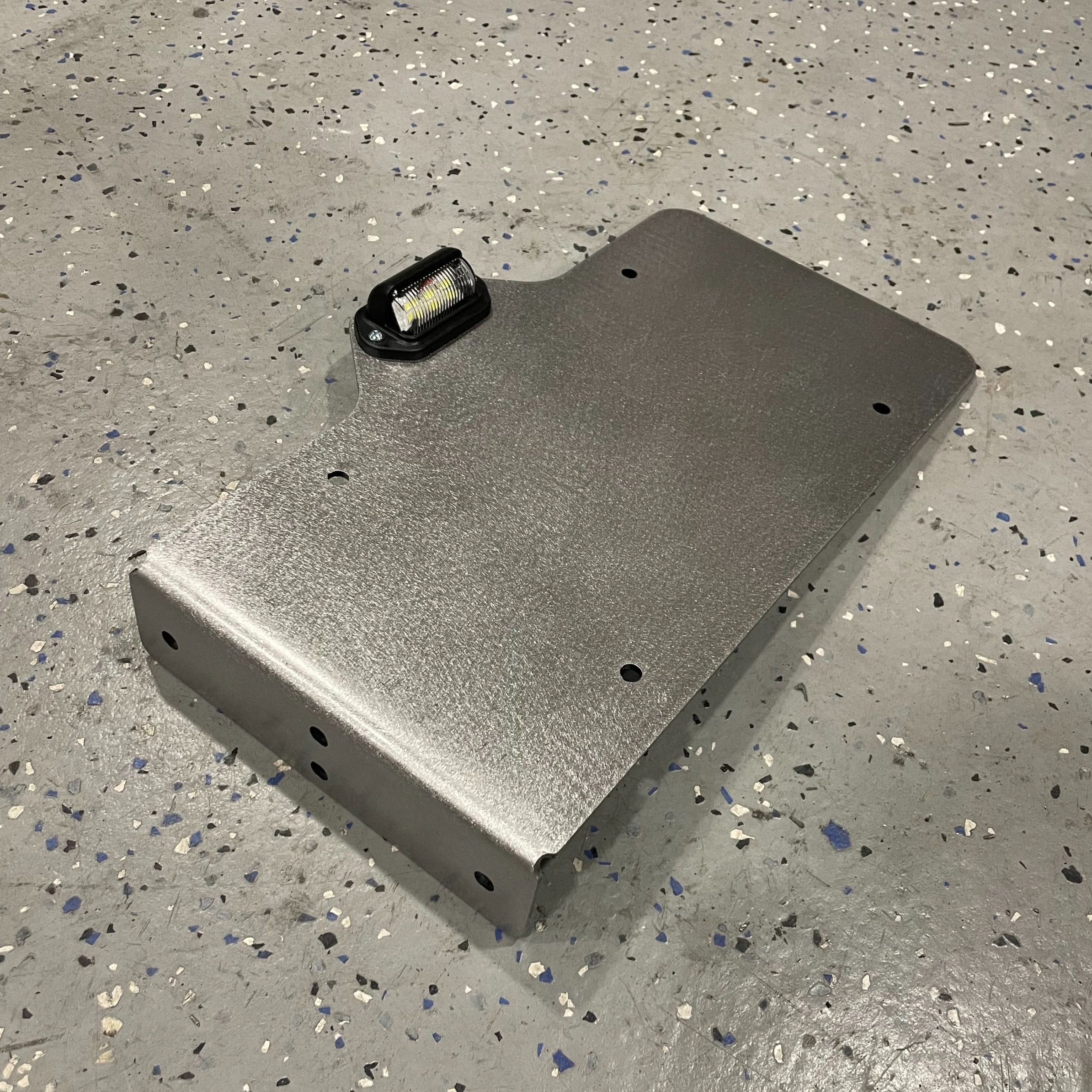 Heavy-duty steel side mount license plate holder for trailer, RV, or semi, with LED light on right side by Elevate Metalcraft.