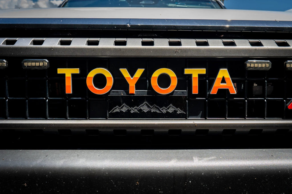 White Toyota Land Cruiser 2024+ front grille emblem overlay by StickerFab, featuring a simple, sleek emblem design.
