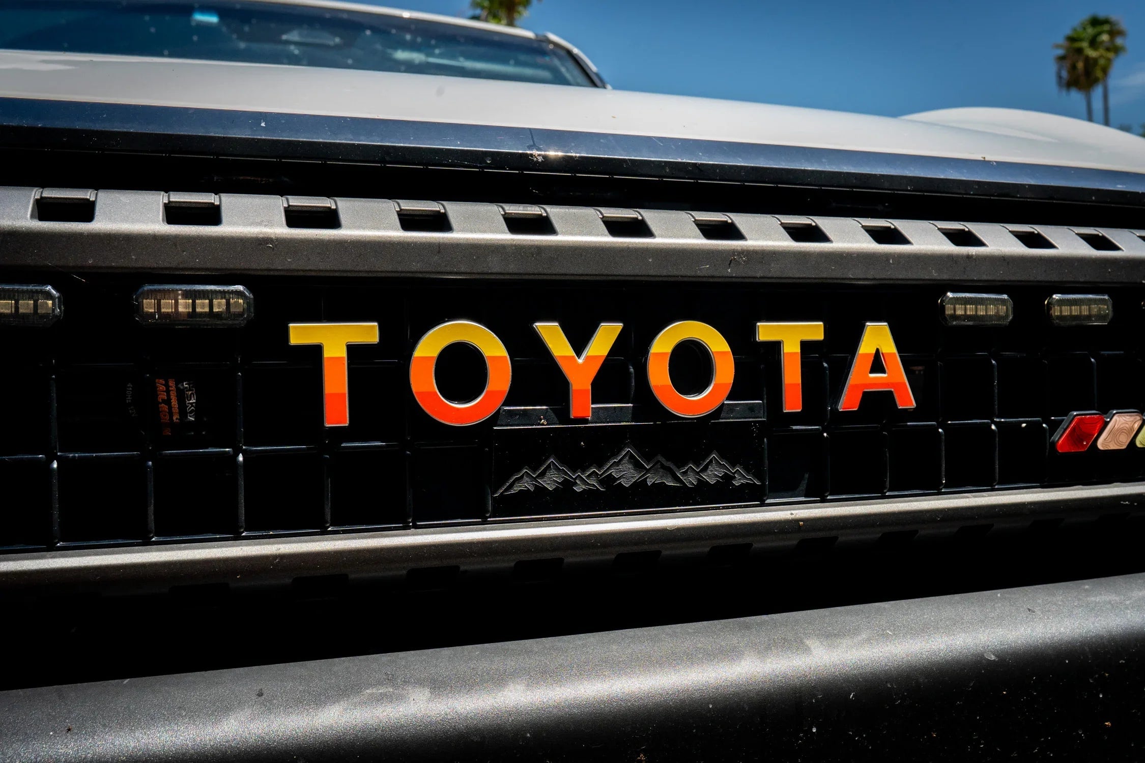 White Toyota Land Cruiser 2024+ front grille emblem overlays by StickerFab, designed for a sleek, custom look.