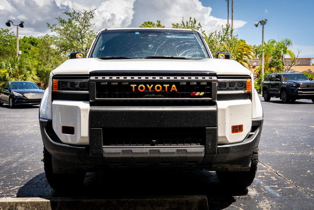 White Toyota front grille emblem overlays for 2024+ Land Cruiser by StickerFab, decorative badge enhancement for vehicle styling.