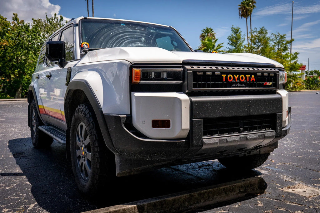 White Toyota Land Cruiser 2024+ front grille emblem overlays by StickerFab, simple and sleek automotive emblem accents.